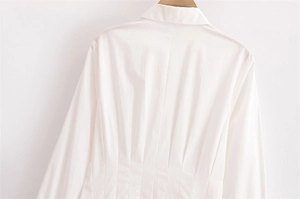 Dettaglio dell'abito midi bianco con pieghe verticali sul retro e vita strutturata
