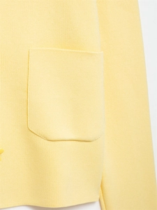 Detail of yellow knit cardigan showing fine jersey texture and pocket stitching