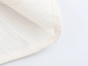 Detailansicht von elfenbeinfarbenem Jacquard-Stoff mit Faltenstruktur und feiner Lochmusterung