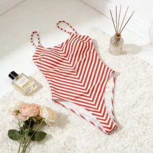Flat lay of red and white striped one-piece swimsuit with thin straps on white rug