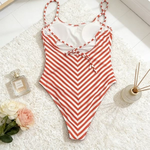 Detail of red and white striped one-piece swimsuit with lace-up back on soft white rug