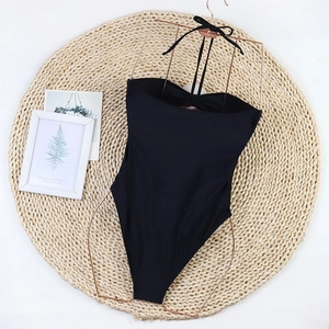 Detail of black halter one-piece swimsuit with ribbon tie on a rose gold metal hanger