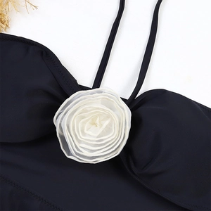 Detailed close-up of a 3D white fabric flower on a black one-piece swimsuit with straps