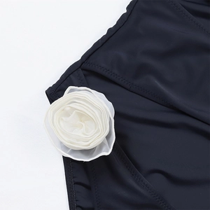 Detail of black swimsuit featuring a large 3D white fabric rose on the side texture