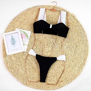 Flat lay of black and white bikini with bow bandeau top on a metallic hanger