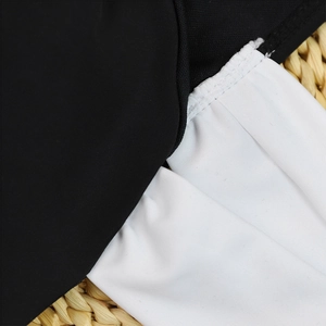 Close-up of contrast stitching and pleated white fabric on a black bikini piece