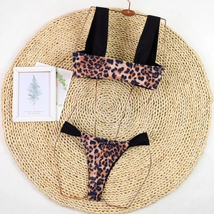 Flat lay of leopard print bikini set on woven mat featuring black straps and side ties