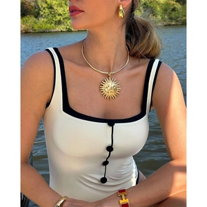 Elegant sun pendant and gold bangles paired with a chic black and white swimsuit