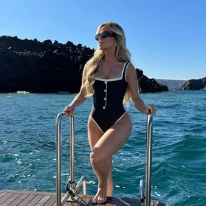 Detail of elegant one-piece swimsuit featuring black contrast with white buttons on a boat