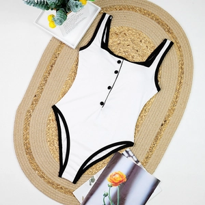 Detail of white ribbed bodysuit with black trim and decorative buttons on front