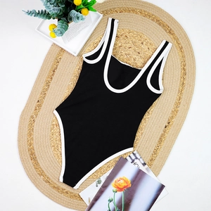 Detail of black one-piece swimsuit with white contrast piping and ribbed texture fabric