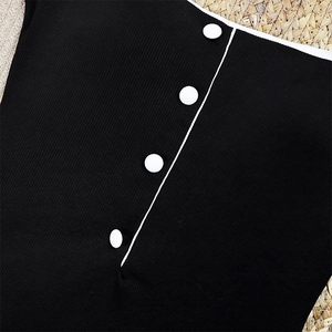 Close-up of black ribbed swimwear featuring contrasting white trim and decorative buttons