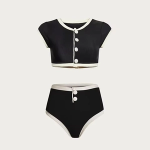 Detail of two-piece bikini featuring white contrast trim and button accents on ribbed fabric