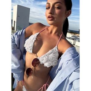 White 3D floral bikini set with pink straps and a blue shirt on a sunny terrace