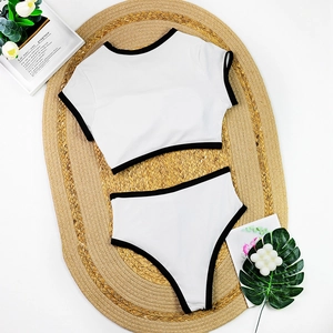 Flat lay of white two-piece bikini with black trim on straw mat with beach decor