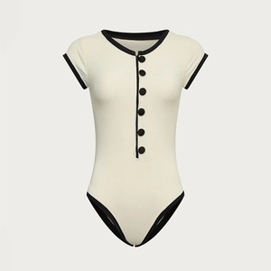 Detailed view of cream bodysuit with black contrast piping and six round buttons