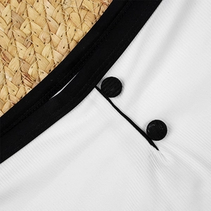 Close-up of white ribbed bikini fabric with black contrast trim and decorative buttons