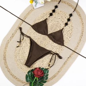 Flat lay of brown halter bikini with geometric beads and gold metallic accents