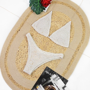 Flachbild des cremeweißen Häkelbikinis mit floraler Spitzenstruktur auf Webmatte