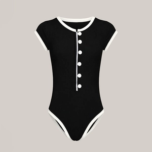 Detailed close-up of ribbed texture and contrast buttons on a black one-piece swimsuit
