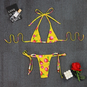 Close-up of yellow bikini set with red cherry print and colorful decorative beads