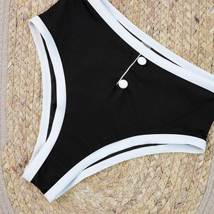 Close-up of black ribbed bikini bottoms with white trim and decorative buttons