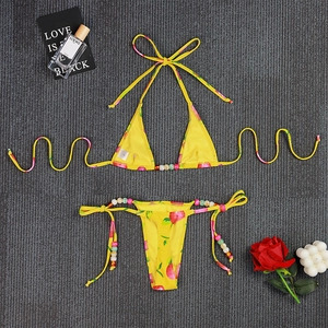 Flat lay of yellow floral print bikini set with neck ties and colorful beaded details