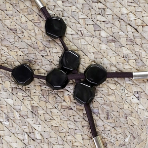 Detail of faceted black beads on a natural straw mat showing textures and elastic cord