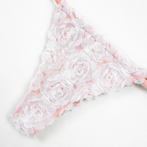 Close-up of pink bikini fabric featuring 3D white lace rose floral texture details