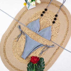 Close-up of gray bikini with hexagonal black beads on braided straw beach mat