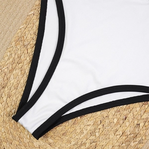 Detail view of white ribbed fabric with black trim on a natural woven straw background