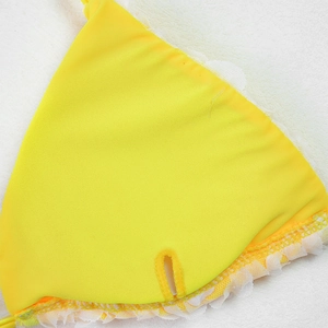 Close-up of vibrant yellow bikini top featuring intricate white lace trim and mesh detailing