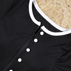 Detail of black ribbed swimsuit neckline with white piping, zipper, and buttons