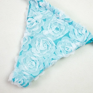 Detailed close-up of 3D white lace floral embroidery on bright blue swimwear fabric
