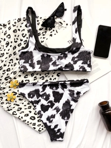 Flat lay of cow print two-piece bikini with high-waisted bottoms and matching cover-up