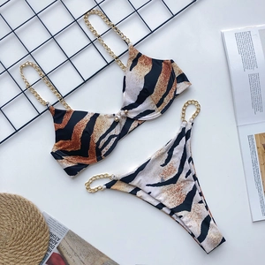 Detail of tiger print bikini with gold chain straps and underwire cups on white background