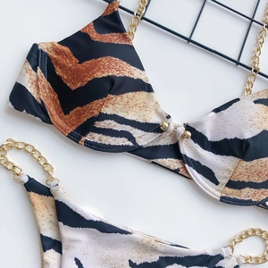 Detail of tiger print bikini with gold chain straps and metal buckle on white background