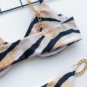 Detail of tiger print bikini with elegant gold metal chain straps on white background