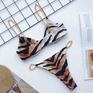 Flat lay of animal print bikini set with stylish gold metal chain straps on top and bottom