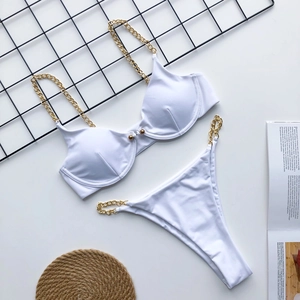 Flat lay of white bikini set featuring gold chain straps and metal buckle details