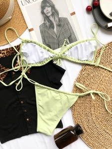 Flat lay of mint green ruched bikini set with tie-side bottoms on a summer resort background