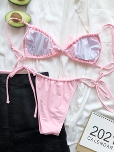 Flat-lay detail of pink ruched bikini set with wash label and stylish summer accessories