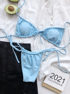 Flat lay of light blue ruched bikini set with adjustable side ties on textured clothing