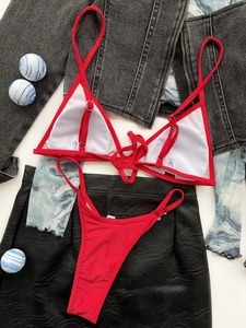 Flat lay of vibrant red triangle bikini set with adjustable straps on dark textured background