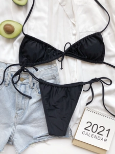 Detailed flat lay of black ruched bikini set with adjustable halter tie and high cut bottom