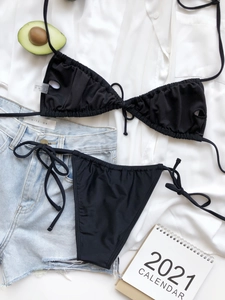 Detailed flat lay of black ruched string bikini set with halter top and tie-side bottoms