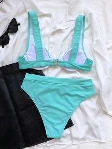 Dettaglio bikini verde menta con spalline larghe e slip a vita alta su camicia bianca classica