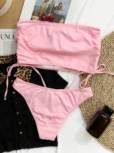 Detailed flat lay of a pink drawstring bandeau bikini with ribbed fabric texture