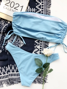 Detail of light blue bandeau bikini set with drawstring side ruching on white background