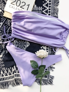 Detailed flat lay of lavender purple drawstring bandeau bikini set on geometric rug
